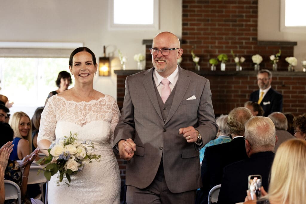 A newly married happy couple smiles as they walk down the aisle after their wedding in Westwood, Massachusetts