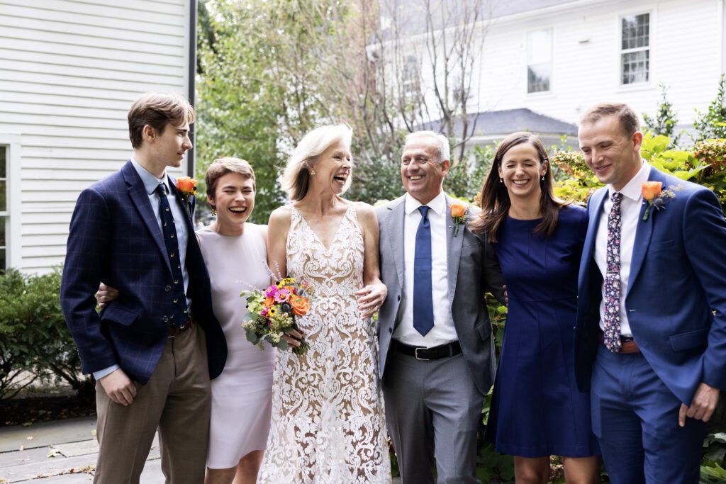 A newly married husband and wife laugh with their adult kids after their wedding in Concord, Massachusetts